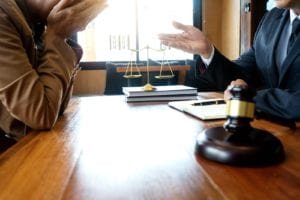 Lawyer talks to client, who has head buried in hands