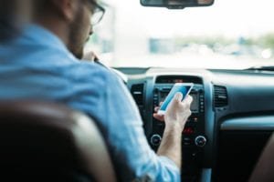 Man on iPhone sitting in driver's seat