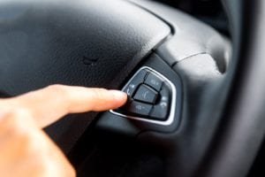 Person pressing cell phone button on steering wheel
