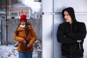 Woman rounds corner while man with knife waits