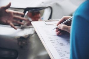 Person checks off car damage information after accident