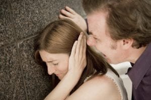 Woman covers her ear as man yells in her face