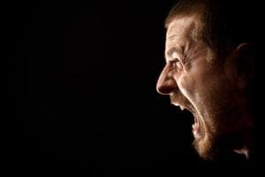 Man screaming against black background