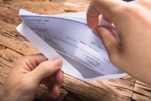 Person opening a check in an envelope from small claims court win