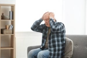 Stressed elderly man holding his head