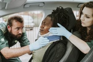 Paramedics placing a cervical collar to an injured woman in car