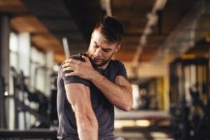 Man feeling pain in the shoulder at the gym