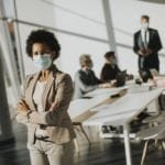 Woman with a mask on stands by conference table