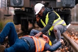 Injured worker lying on the ground while his coworker calls for help
