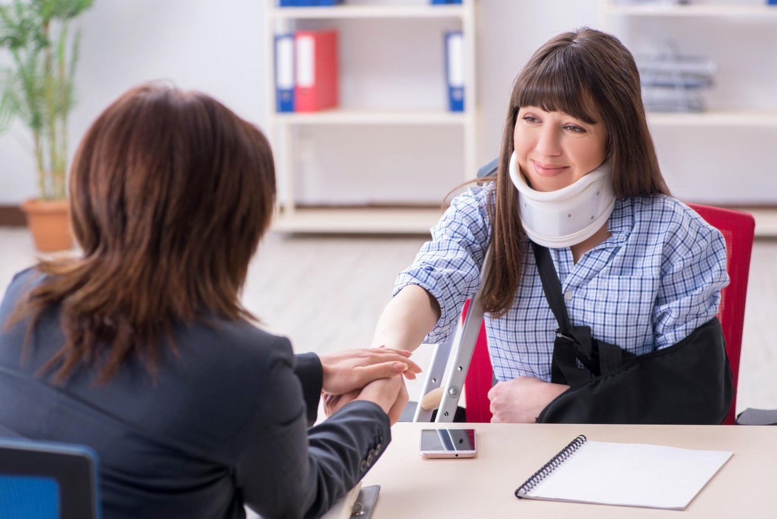 Injured woman shaking hands with her lawyer