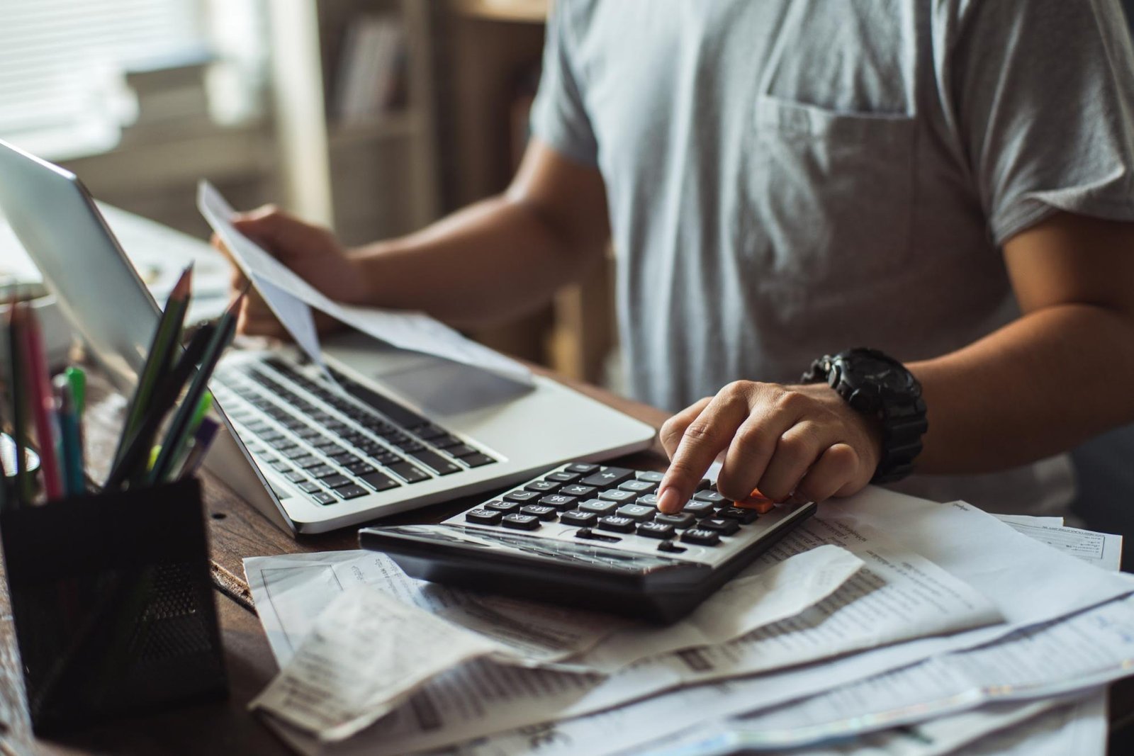 Man computing his bills using a calculator at his desk
