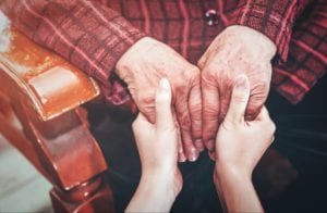Young girl's hands holding the hands of an elderly