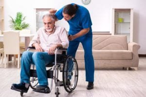 Old man in a wheelchair with an angry male caregiver