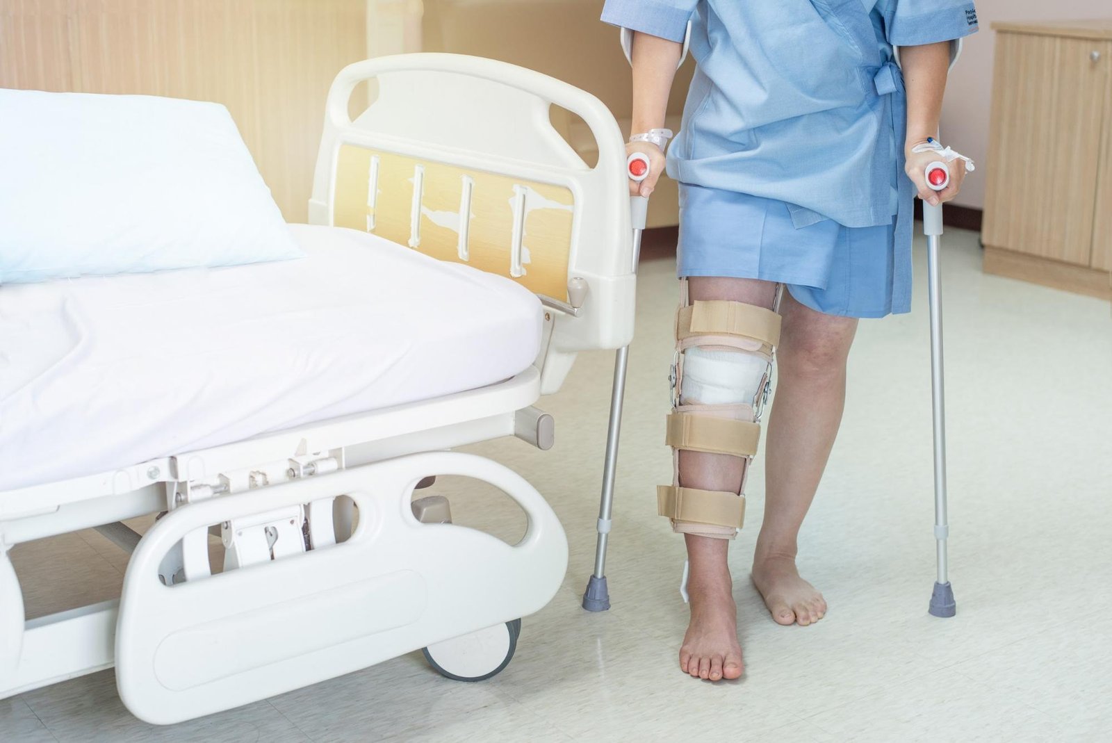 Patient with a knee brace and walking sticks in a hospital room
