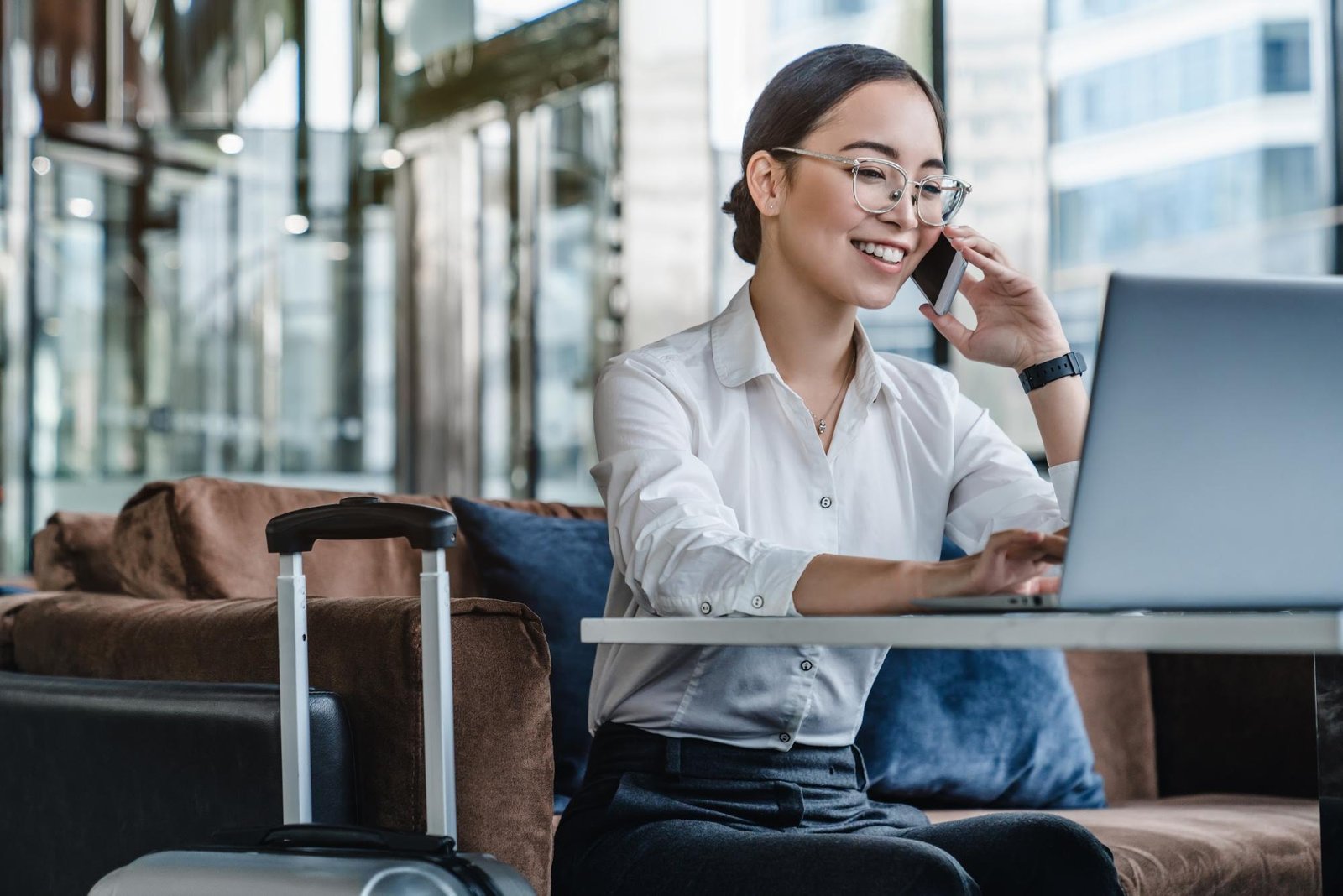 Smiling woman on the phone while working at an airport lounge