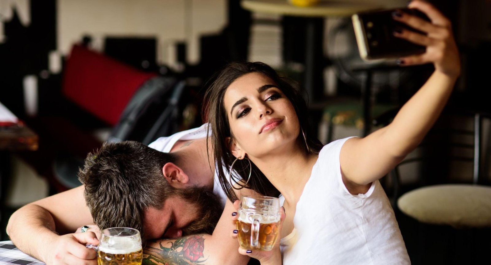 Woman taking a selfie with an intoxicated man behind her