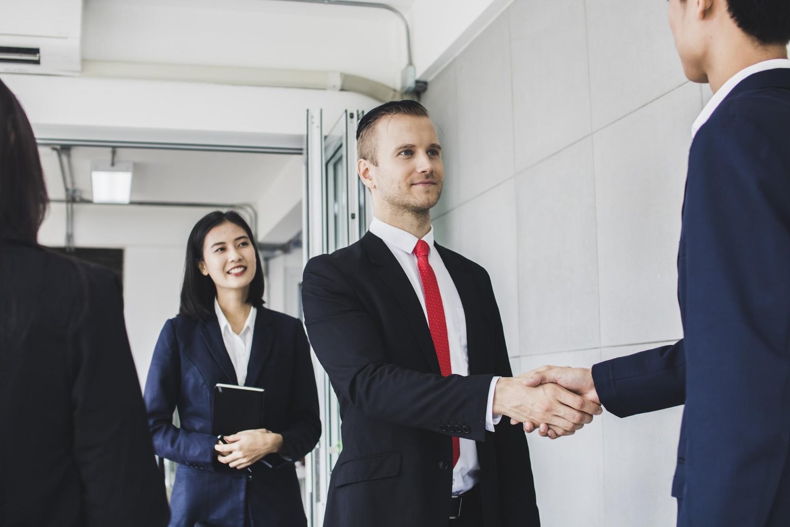 Businessmen shaking hands with one of their colleagues smiling near them