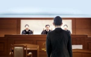 Man standing in front of the judges in a courtroom