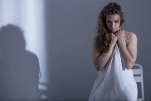 Bruised woman holding a white sheet against her body
