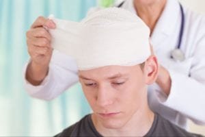Doctor assisting a male patient with head injury
