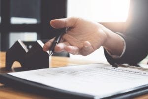 Person's hand holding a pen with a contract on the table