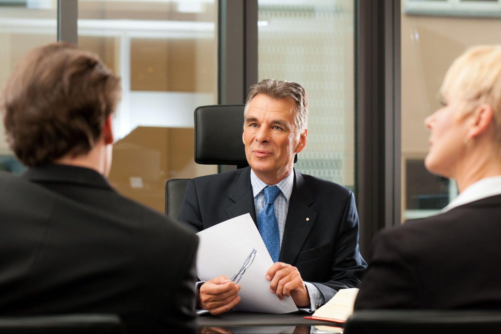 Lawyer talking to his clients while holding his glasses and a sheet of paper