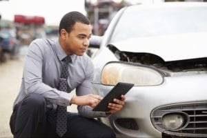 man looking at his car while holding a tablet