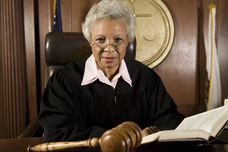 Elderly judge in a courtroom and looking at the camera 