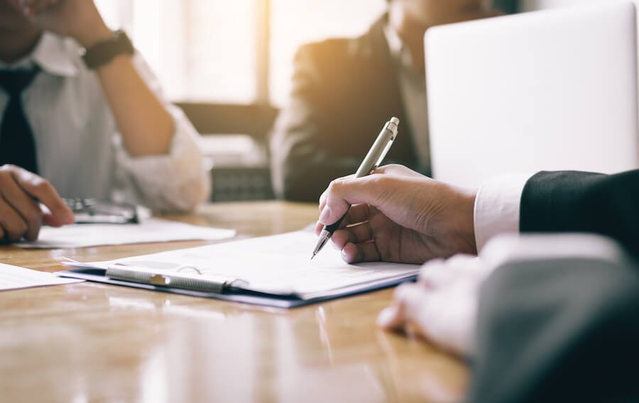 Man writing on a clipboard during a meeting