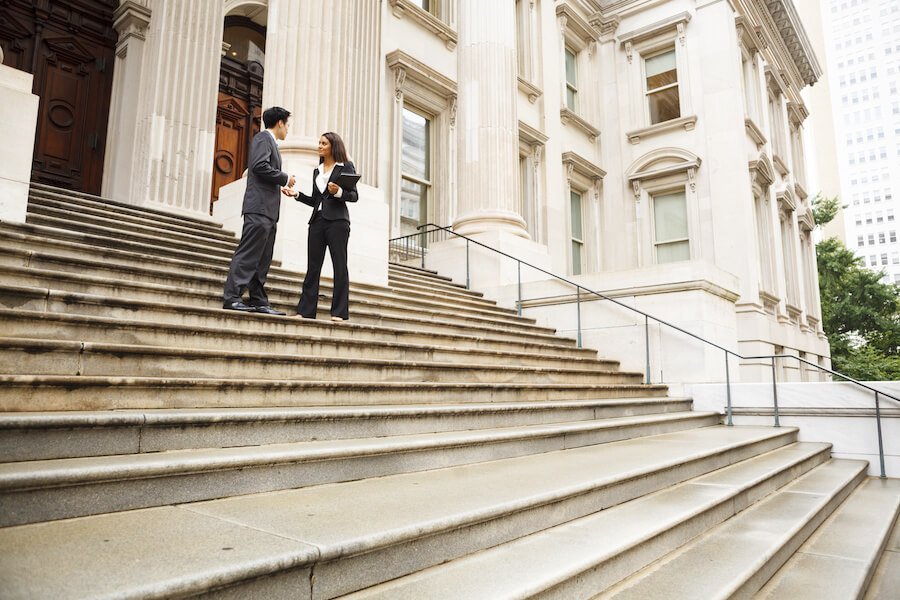 Two colleagues having a discussion on the front steps of a building