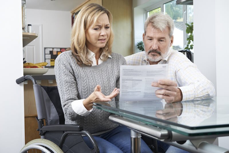 Woman in a wheelchair discussing a document with her husband