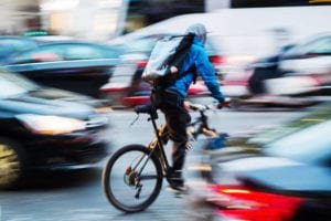 Man riding a bicycle with blurred cars in the background